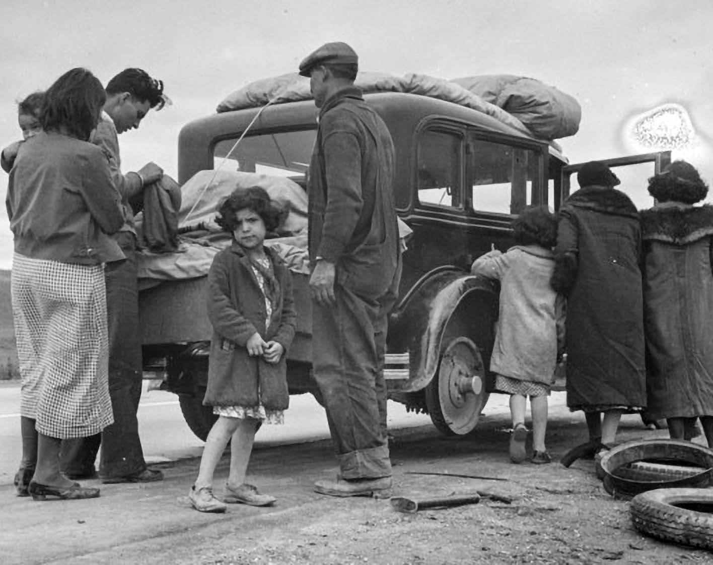Immigrants posing in front of car packed with luggage